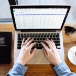 person using laptop with planner and coffee