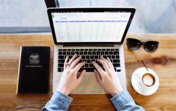 person using laptop with planner and coffee