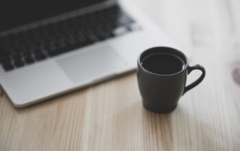 financial charts, laptop, coffee cup, casual work setup