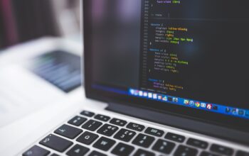 programmer coding on laptop with compliance icons